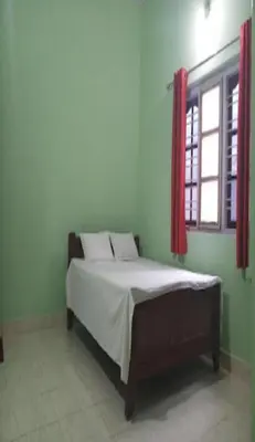 a bedroom with a bed and a window with red curtains at Devarakadu Valley View by StayApart in Madikeri