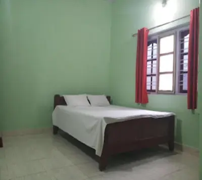 a bedroom with a bed and a window with red curtains at Devarakadu Valley View by StayApart in Madikeri