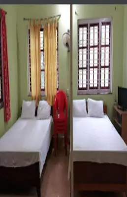 a bedroom with two beds and a red chair at Devarakadu Valley View by StayApart in Madikeri