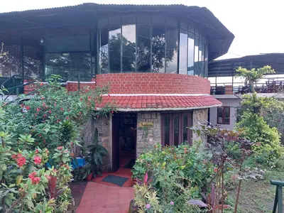 a building with a small house with flowers in front of it at THE TIGER PAW RESORT in Masinagudi