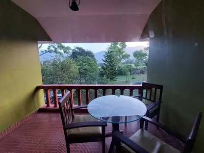 a table and chairs on a balcony with a view at THE TIGER PAW RESORT in Masinagudi