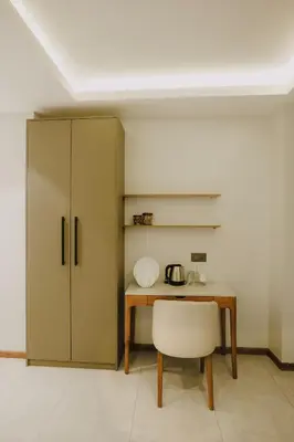 a kitchen with a table and a chair and a cabinet at Alite Enclaves Fully furnished apartments in Trichūr