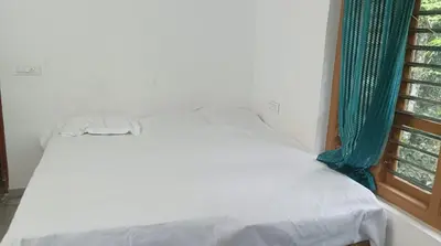 a white bed in a room with a window at CRS RED & WHITE HOMESTAY in Sultan Bathery