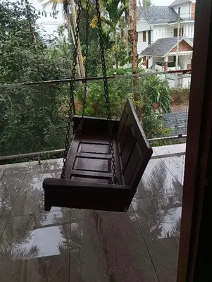 a swing hanging from a balcony in the rain at CRS RED & WHITE HOMESTAY in Sultan Bathery