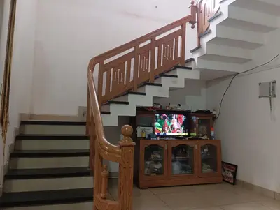a living room with a staircase with a tv and a cabinet at CRS RED & WHITE HOMESTAY in Sultan Bathery