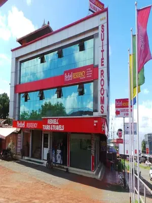 a building with red and white signs on it at Redbell suites Residency in Kondotti