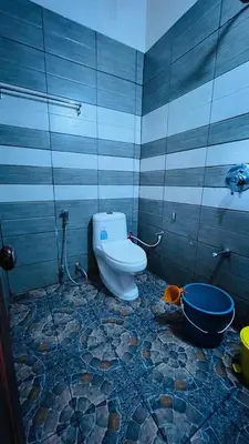 a bathroom with a toilet and a blue and gray wall at Golden Cypress Resort with Pool -Wayanad in Padinjarathara