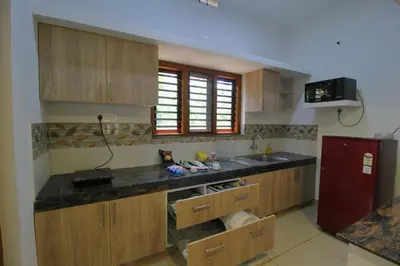 a kitchen with wooden cabinets and a red refrigerator at TreeSong Villa - Tranquil Forest Villa in Wayanad in Sultan Bathery