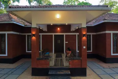 a woman sitting on the balcony of a house at TreeSong Villa - Tranquil Forest Villa in Wayanad in Sultan Bathery