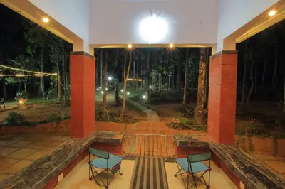 a room with two chairs and a view of a forest at TreeSong Villa - Tranquil Forest Villa in Wayanad in Sultan Bathery