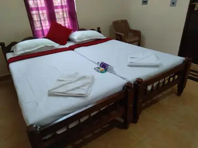 a large bed with white sheets and towels on it at Homely Homestay in Kalpetta