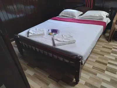 a bed with two towels and a pair of shoes on it at Homely Homestay in Kalpetta