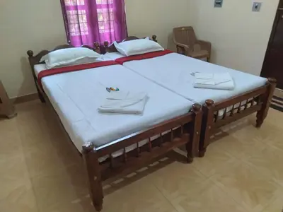 a large bed with white sheets and towels on it at Homely Homestay in Kalpetta