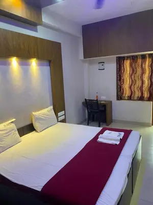 a bedroom with a large white bed and a desk at Redbell Suites Calicut in Kozhikode
