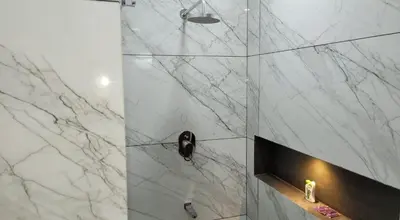 a bathroom with a shower with a marble wall at Amminis Mansion by Doris Homes in Trichūr