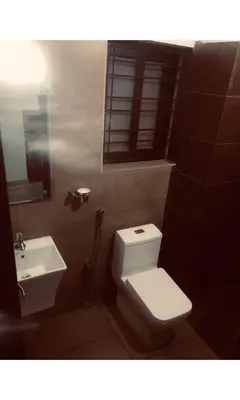 a bathroom with a white toilet and a sink at Redbell Inn Airport Hotel in Kondotti