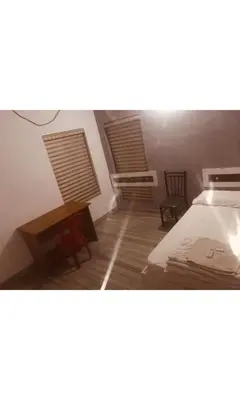 a bedroom with a bed and a desk and two windows at Redbell Inn Airport Hotel in Kondotti