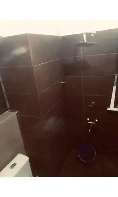 a bathroom with a toilet and a shower with brown tiles at Redbell Inn Airport Hotel in Kondotti
