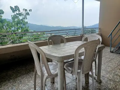 a table and chairs on a balcony with a view at Wander homes in Ooty