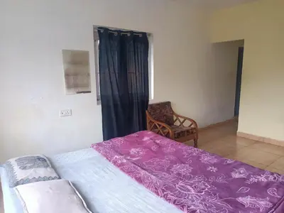 a bedroom with a bed with purple sheets and a chair at Wander homes in Ooty