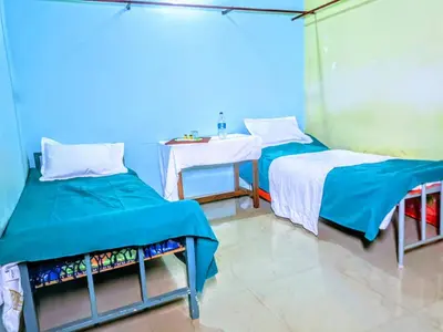 a room with two beds and a table in it at VKR MENS ROOM (Gents Only) in Kozhikode