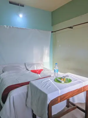 a bed with a table with a bottle of water on it at VKR MENS ROOM (Gents Only) in Kozhikode
