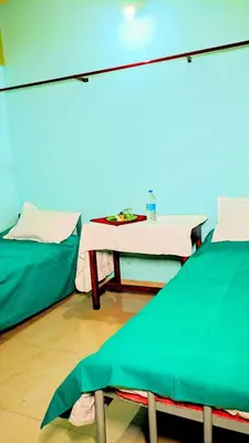 a hospital room with two beds and a table at VKR MENS ROOM (Gents Only) in Kozhikode
