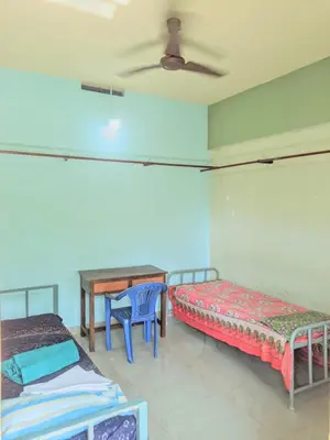 a room with two beds and a table in it at VKR MENS ROOM (Gents Only) in Kozhikode