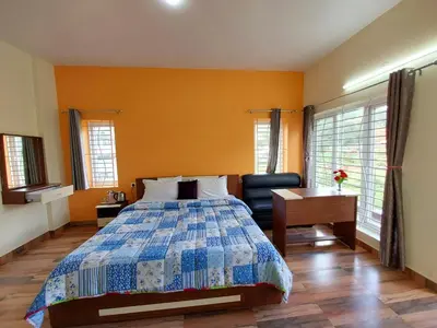 a bedroom with a bed and a chair and windows at Serenity inn - Rose Garden in Ooty