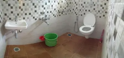 a bathroom with a sink and a toilet and a bucket at Green Land Estate Homestay 5 Rooms With Garden View in Madikeri
