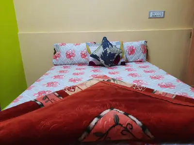 a bed with a red blanket and pillows on it at Green Land Estate Homestay 5 Rooms With Garden View in Madikeri