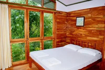 a bedroom with a bed in a room with windows at Solitude Munnar - Tree house in Munnar