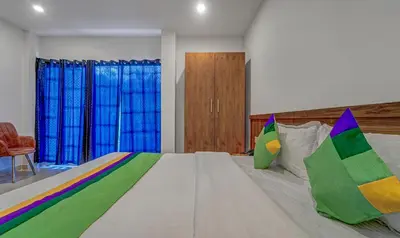 a bedroom with a large bed with colorful pillows at Treebo Regalia Inn Wayanad With Swimming Pool in Kalpetta