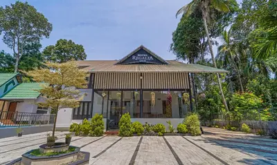 a building with a tree in front of it at Treebo Regalia Inn Wayanad With Swimming Pool in Kalpetta