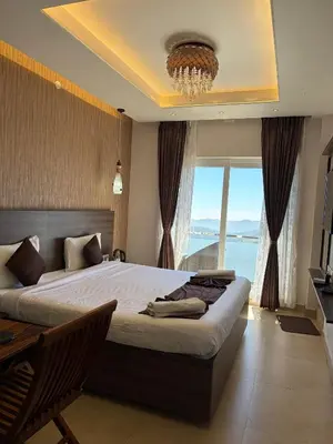 a bedroom with a large bed and a large window at Vanam Holidays in Ooty