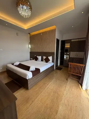 a bedroom with a large bed and a chandelier at Vanam Holidays in Ooty