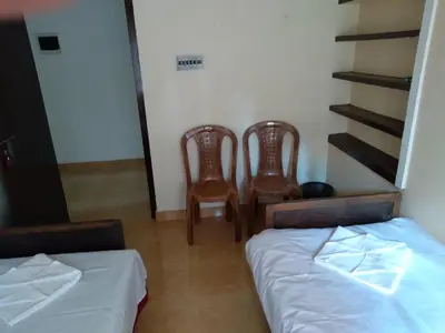 a room with two beds and two chairs in it at Homely Homes in Kalpetta