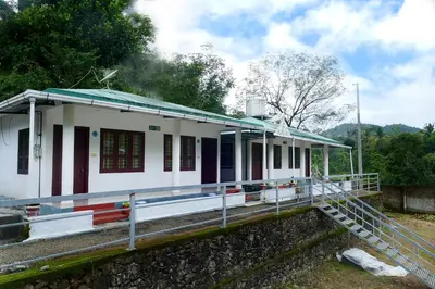 a white building with a staircase in front of it at Mountain View cottage Mankulam in Munnar