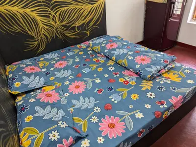 a bed with a blue blanket with flowers on it at kaffee valley - Kurumbalakotta in Padinjarathara