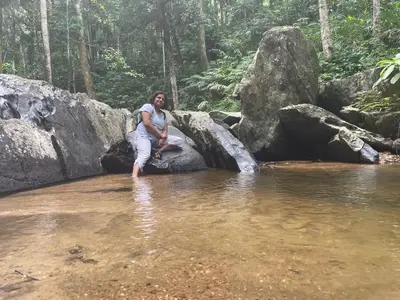 a woman sitting on a rock in a body of water at Rai’s Coorg Cave House in Madikeri