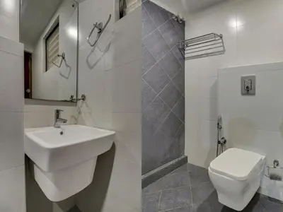 a white bathroom with a sink and a toilet at Rotano Glitz Inn - Glitz Inn Calicut in Kozhikode