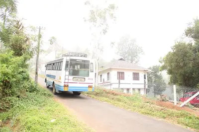 a bus driving down a road in front of a house at The Lavender Woods in Vythiri