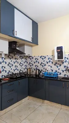 a kitchen with blue cabinets and blue and white tiles at SindooRa in Mysore