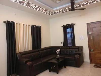 a living room with a brown leather couch and curtains at SindooRa in Mysore