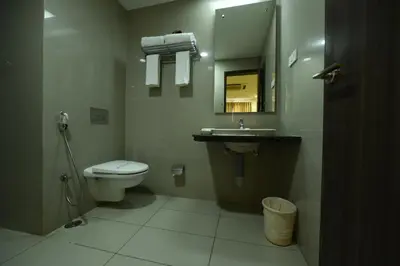 a bathroom with a toilet and a sink and a mirror at Hotel LandmarK Coimbatore in Coimbatore