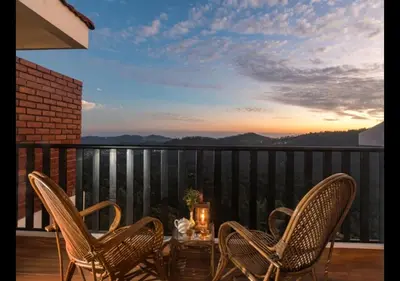 a table and chairs on a balcony with a sunset at Sleeping Beauty by Nature Resorts and Stays in Coonoor