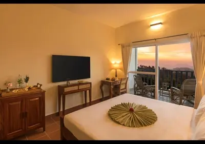 a bedroom with a bed and a television and a balcony at Sleeping Beauty by Nature Resorts and Stays in Coonoor