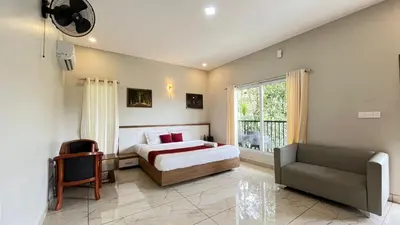 a bedroom with a bed and a chair and a window at Mountain Vibes Resort Wayanad in Wayanad