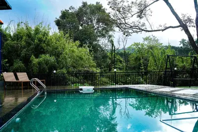 a swimming pool with a black fence and trees at Caravan holiday homes Vythiri in Vythiri