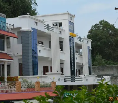 a white building with a sign in front of it at Pinehill Suites in Ooty